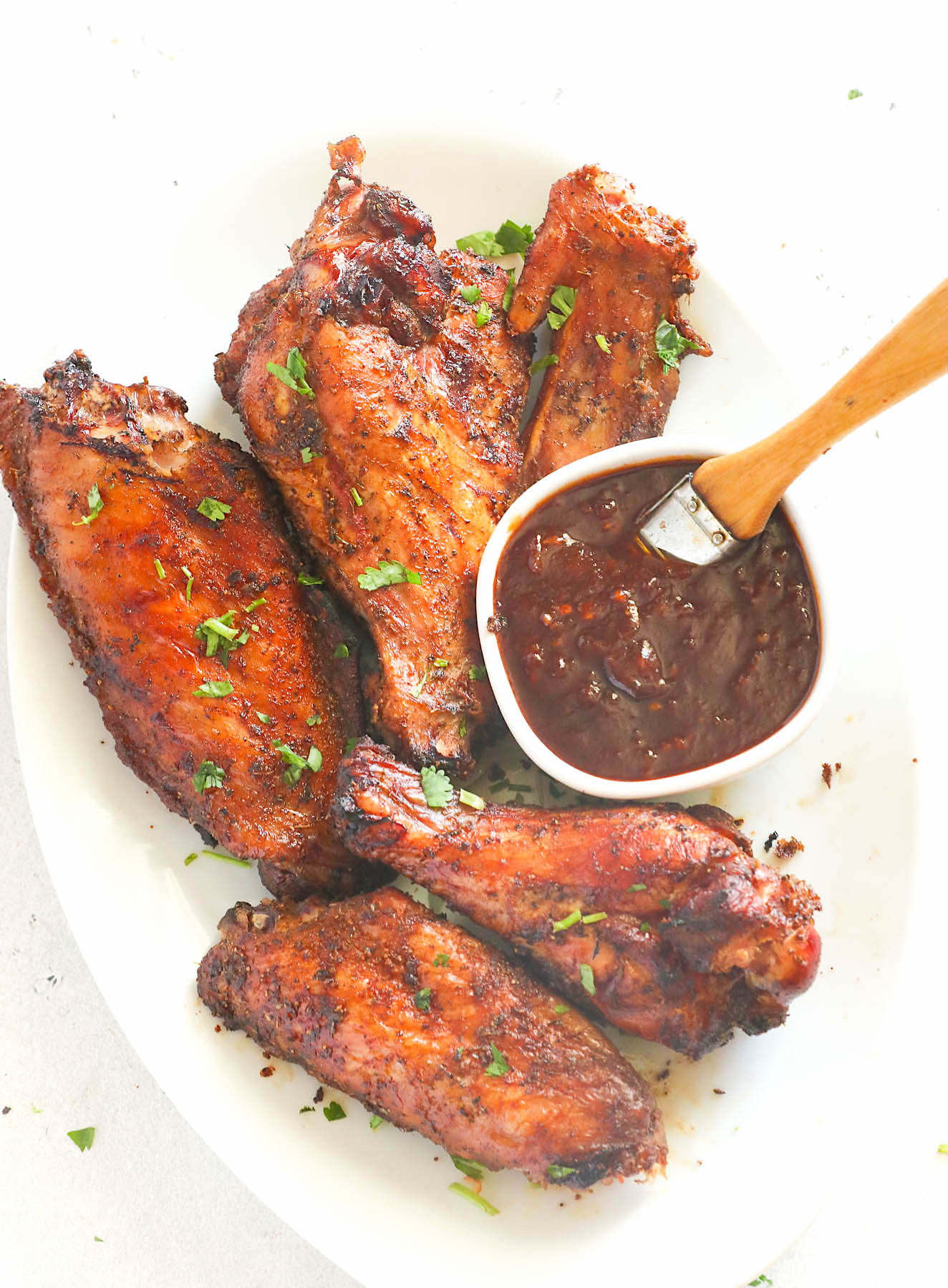 Basting crazy delicious smoked turkey wings with BBQ sauce