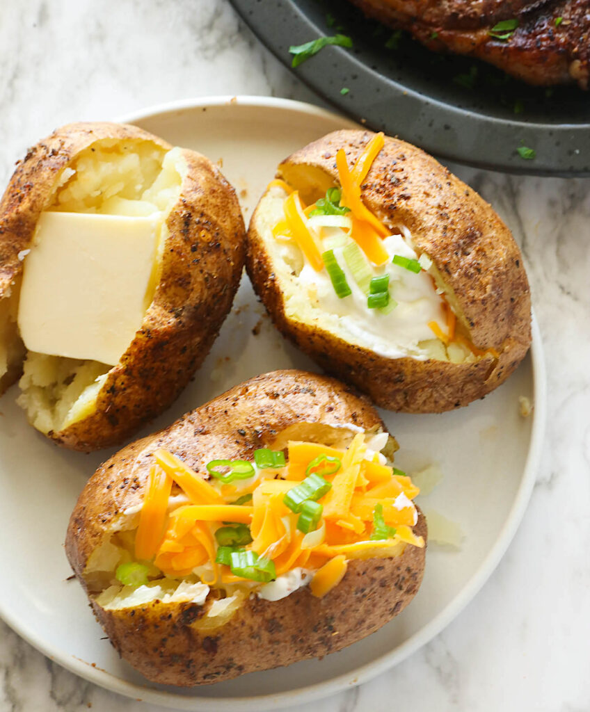Loading up deliciously smokey baked potatoes witih cheese and green onions
