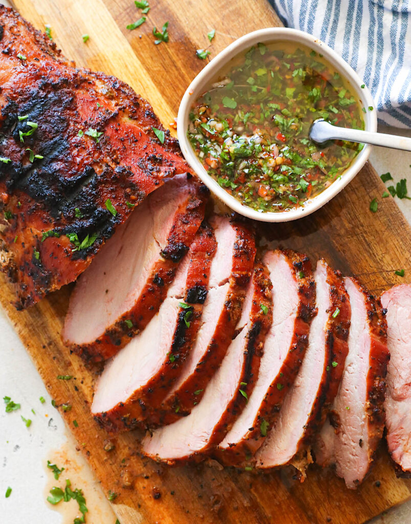 Sliced and ready to serve pellet grill smoked pork loin with chimichurri