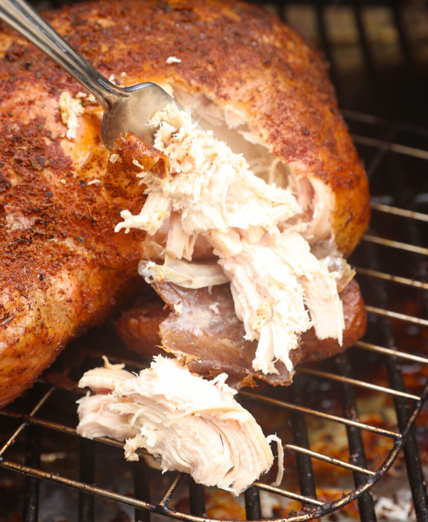 Smoked pulled chicken being prepared in a smoker: Juicy and tender pulled chicken slowly infusing with smoky flavors as it cooks inside the smoker.
